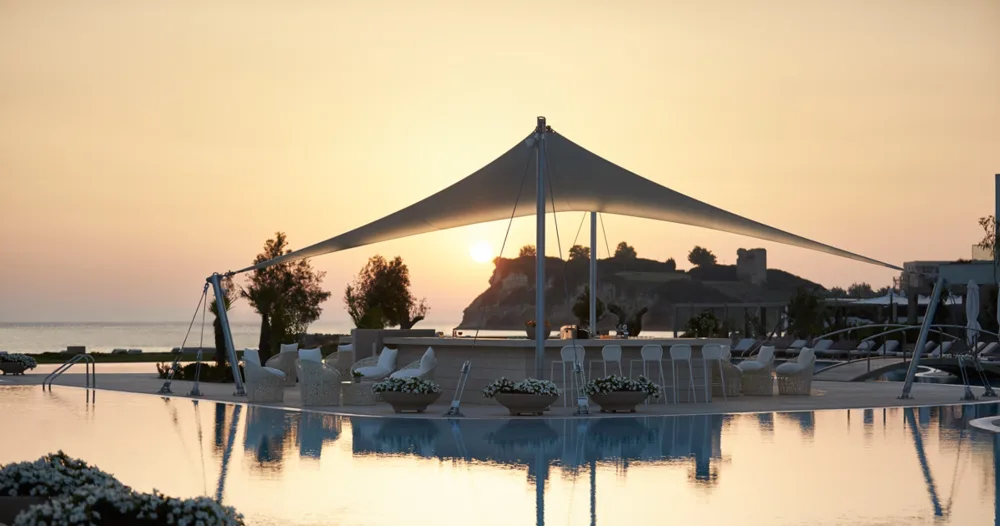 A poolside terrace overlooking the sea at sunset