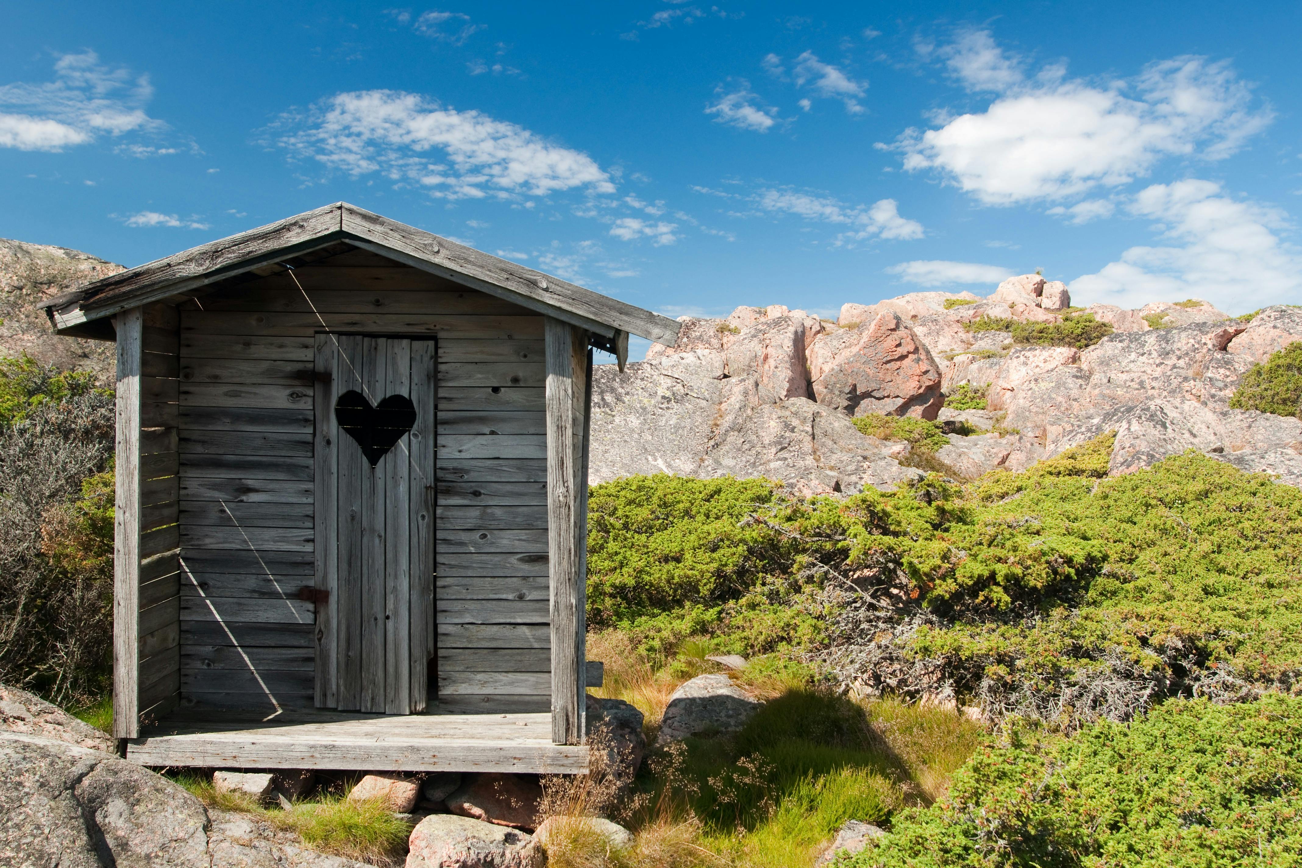 A wooden cabin in a rocky landscape under a clear sky.