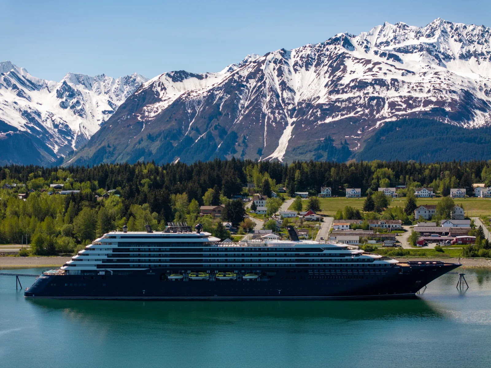 Luminara alongside an Alaskan coastal town beneath snow-covered mountains