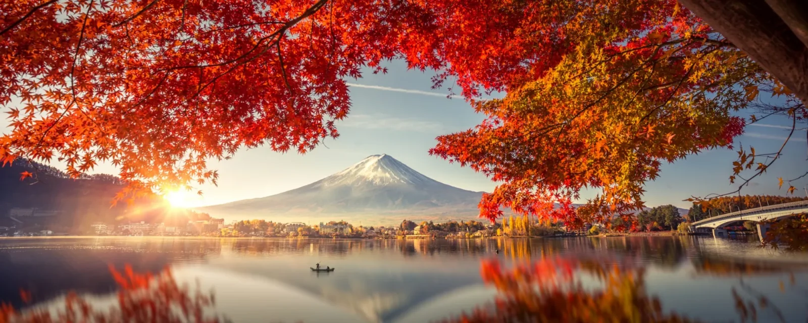 Mount Fuji across a lake framed by red autumn leaves